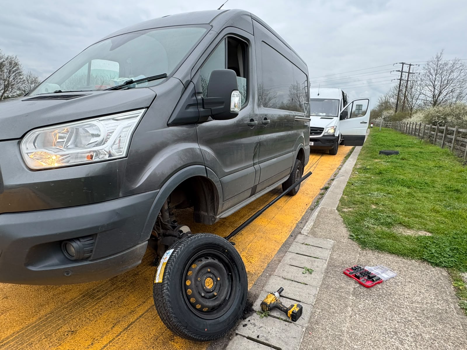 Roadside wheel change on a Ford Transit van on a yellow-lined verge